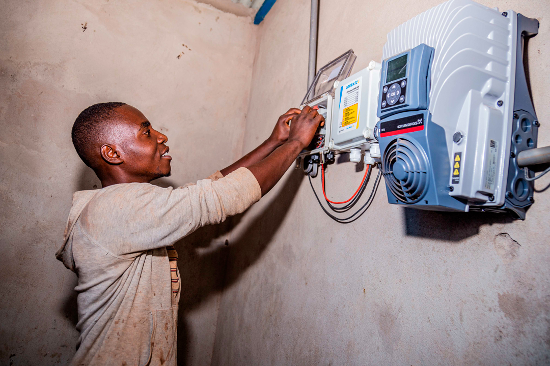 Sylvestre Mpawenayo (26), Gebäudewart und Betreiber eines Brunnens in Kubinaro, Burundi, schaltet die solarbetriebenen Wasserpumpen ein.